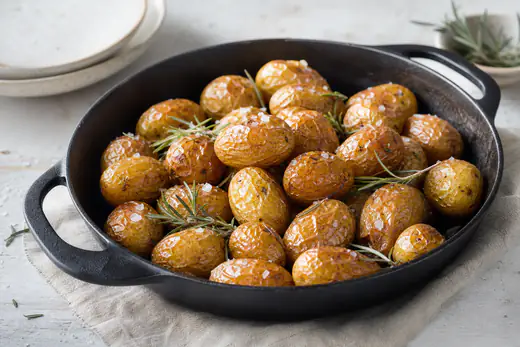 Rostad minipotatis med gyllene skal, flingsalt och rosmarin i en gjutjärnspanna