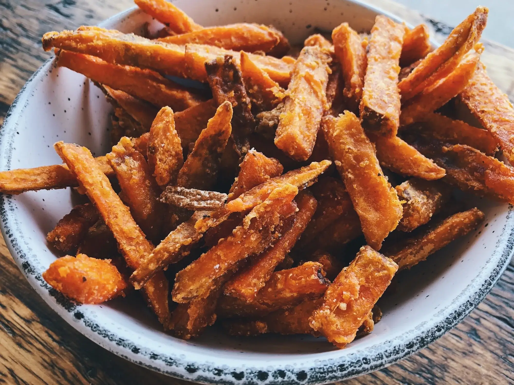 Krispiga sötpotatisfrites i airfryer med gyllenbrun yta.